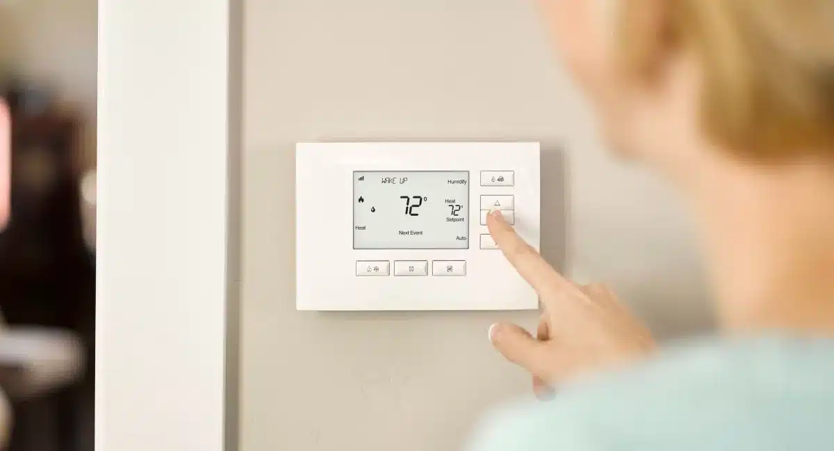 Control4 smart thermostat being adjusted on a wall